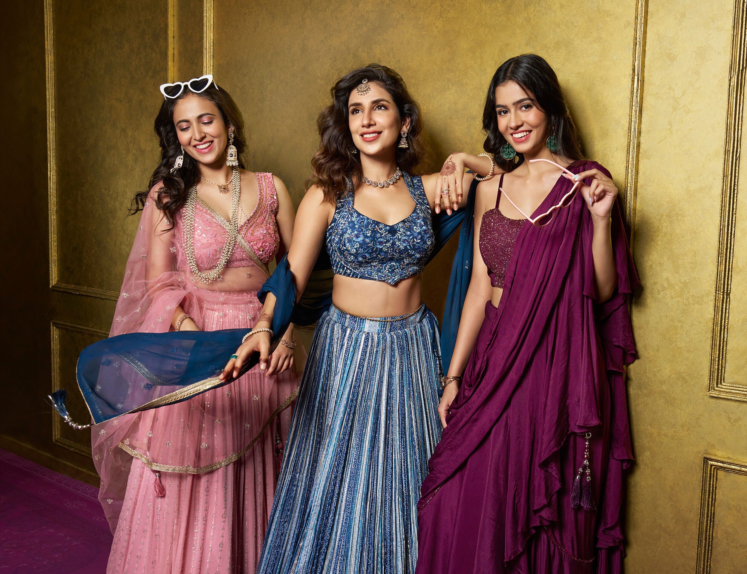 A bride and bridesmade wearing different colour lehengas